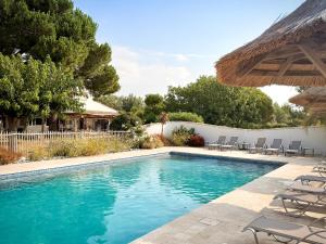 a swimming pool with chairs and an umbrella at Hotel Mas Des Barres in Saintes-Maries-de-la-Mer