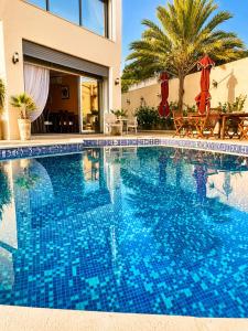 a swimming pool with blue tiles in front of a house at Chez Roberto in La Marsa