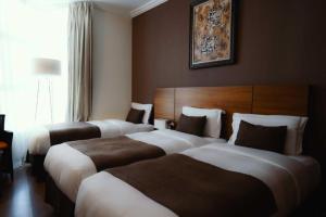 a hotel room with three beds and a window at Elaf Almaqamah Nour Althuria Hotel in Mecca