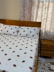 a bed with white sheets and pillows next to a window at The Cozy Nest in Tanga