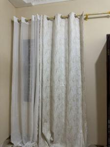 a white curtain hanging on a rod in a room at The Cozy Nest in Tanga