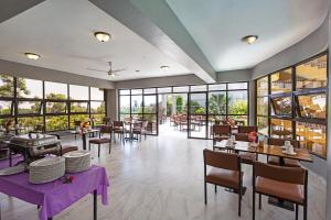 a restaurant with tables and chairs and windows at Roswam Hotel in Keruguya