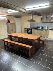 a large kitchen with a wooden table and benches at L’alambic in Guizengeard