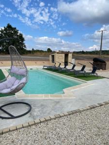 a swimming pool with two chairs and a wicker chair at L’alambic in Guizengeard +4 photos