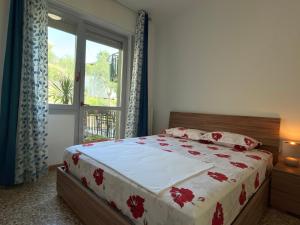 ein Schlafzimmer mit einem Bett mit roten Blumen darauf in der Unterkunft Dilman appartamento in Poggiridenti