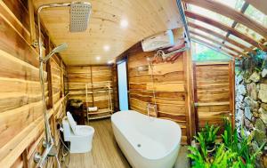 a bathroom with a tub and a toilet in a room with wooden walls at Sunny Camping Sóc Sơn in Sóc Sơn +94 photos