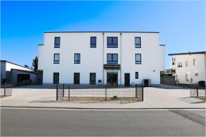 a white building with a fence in front of it at Pension Malia in Fronhausen