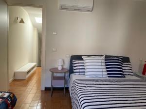a bedroom with a bed with striped pillows and a table at Casa Ficcanaso in Caorle