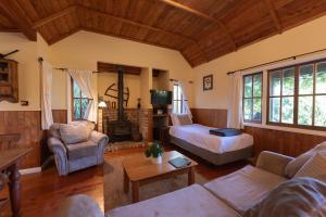 a living room with a bed a couch and a fireplace at Vineyard Cottages - Kumeu in Waimauku +74 photos