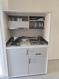 a small kitchen with white cabinets and a sink at Evita Flamingo in Kos