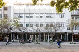a large white building with people walking in front of it at ONOMO Hotel Foreshore in Cape Town