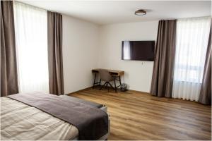 a bedroom with a bed and a desk and a television at Pension Malia in Fronhausen