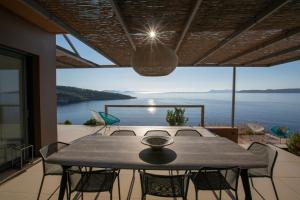 a dining table with chairs and a view of the water at Villa Arkoudaki Luxurious Escape with Infinity Pool & Sea Access in Évyiros