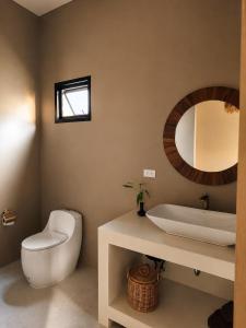 a bathroom with a toilet and a sink and a mirror at La Caza Sowana in Ko Phangan +1 photo
