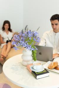 a table with a vase with purple flowers and a laptop at Masseria Stella in Gioia del Colle