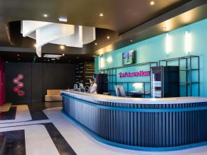 a woman standing at a bar in a restaurant at Ibis Styles Barretos in Barretos