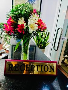 a vase of flowers sitting on a table with a sign at Happy Night Holiday Inn in Unawatuna