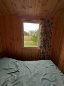 a bed in a wooden room with a window at Na Kocankach - Domki na wyłączność in Czarnoszyce