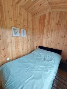 a bed in a wooden room with two pictures on the wall at Na Kocankach - Domki na wyłączność in Czarnoszyce
