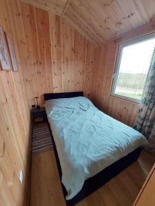 a bed in a wooden room with a window at Na Kocankach - Domki na wyłączność in Czarnoszyce