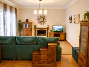 a living room with a green couch and a television at Chalet Duna in El Palmar