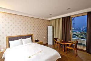 a bedroom with a bed and a table and a window at Geoje Ocean Hotel in Geoje