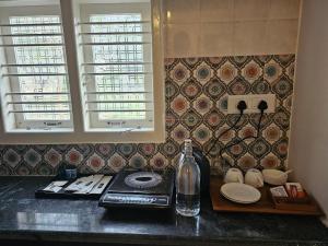a kitchen counter with a bottle and plates and windows at Hotel Ferro in Kumbalgod
