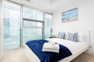 a white bedroom with a large window and a bed at Downtown Toronto CN tower Condo in Toronto