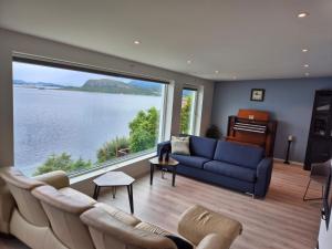 a living room with a blue couch and a large window at Villa with a view in Ålesund