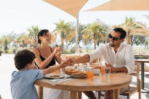 a family sitting at a table holding hands at Santo Miramare Beach Resort in Perivolos