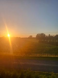 a sun setting over a field with a road at Boose Apart in Kobela