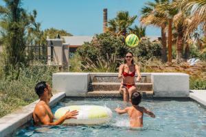 a woman in a swimming pool with two children and a frisbee at Santo Miramare Beach Resort in Perivolos