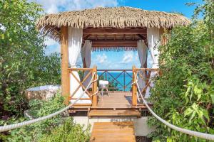 a wooden walkway leading to a hut with a thatch roof at Villa with exclusive views in Marigot