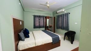 a bedroom with a bed and a chair in it at Fabhotel Aman palace in Mumbai