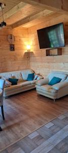 a living room with two couches and a flat screen tv at Dom na wyłączność U Eskulapa in Lutowiska
