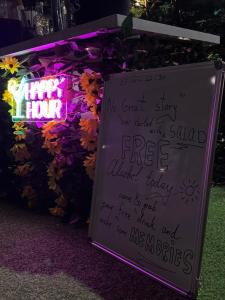 a sign with writing on it in front of a wall of flowers at Santa5 hostel in Vlorë