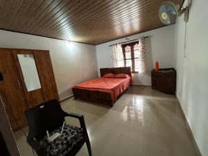 a bedroom with a bed and a chair in a room at Kds Homestay in Gonikoppal