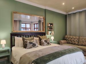 a bedroom with a bed with a mirror and a couch at Rozenhof Guest Cottages in George