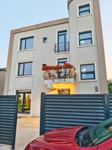 a building with a balcony with red flowers on it at Otopeni Garden Hotel in Otopeni