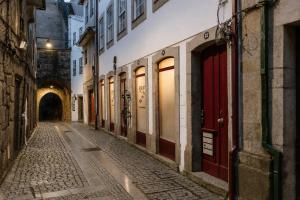 an empty alley with red doors in an old building at Ribeirinha Guesthouse in Guarda