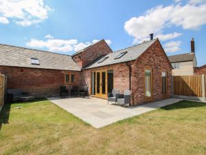 a brick house with chairs on a patio at Chestnut Barn in Shrewsbury