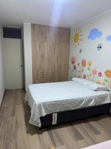 a bedroom with a bed and a wall with flowers at Casa Almara - Ica in Ica