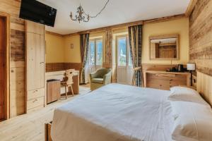 a bedroom with a large bed and a desk at Hotel Corona in Cortina dʼAmpezzo