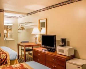 a hotel room with a bed and a television on a desk at Rodeway Inn Kalkaska in Kalkaska