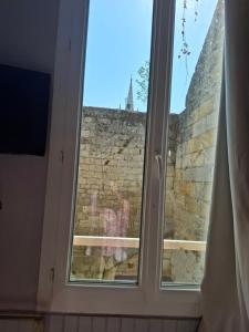 a window with a view of a brick wall at Studio en toute simplicité plein centre in Libourne