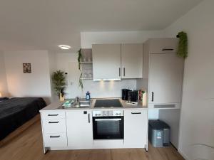 a kitchen with white cabinets and a sink and a bed at Wohnglück Leer City Nr 3 in Leer