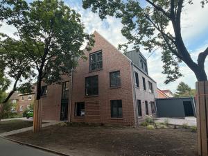a brick building with a tree in front of it at Wohnglück Leer City Nr 3 in Leer