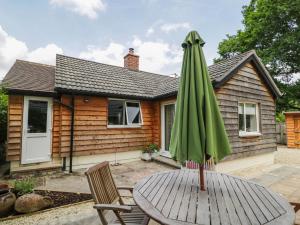 a green umbrella sitting on a table in front of a house at Little Orchard in Swallowcliffe