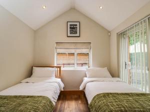 two beds in a room with a window at Little Orchard in Swallowcliffe