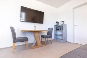 a table with two chairs and a television on a wall at Bluemlisalp Studio - Aare Jungfrau AG in Spiez